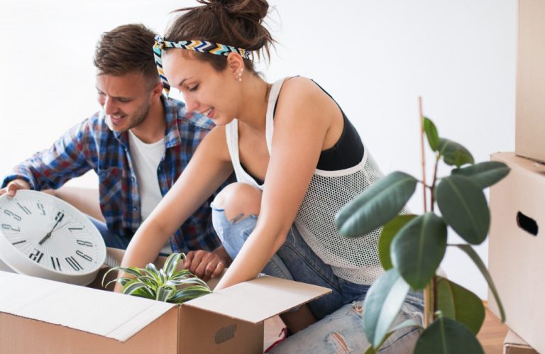 couple putting plants inside a box before moving