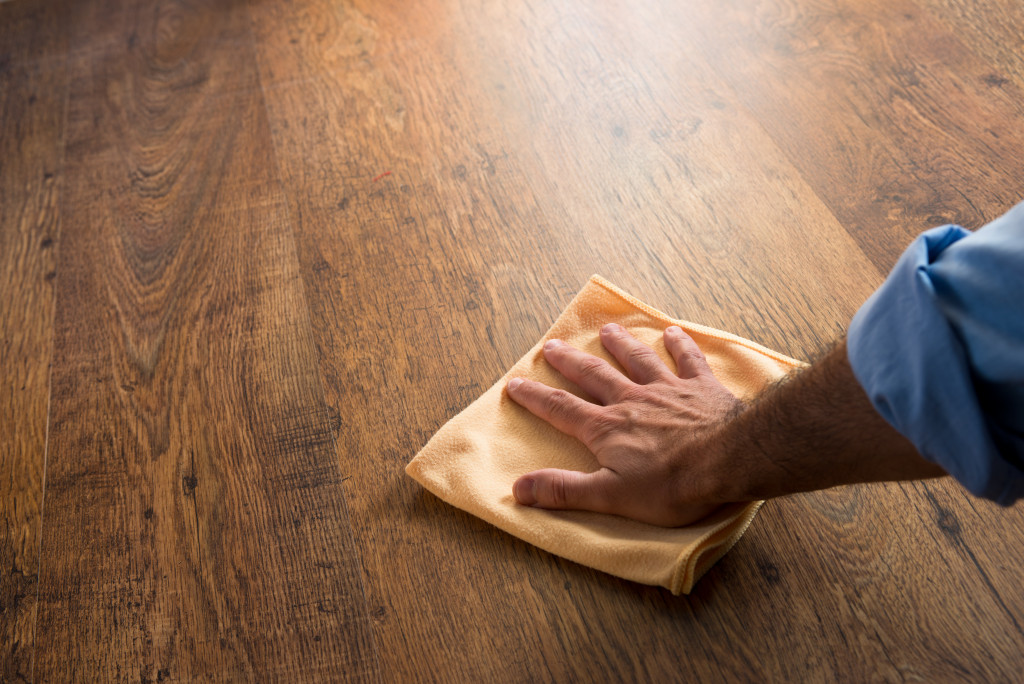 A person rubbing a hardwood floor with a microfiber cloth
