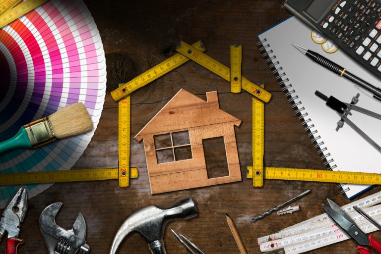 A wooden cutout of a house surrounded by various construction supplies