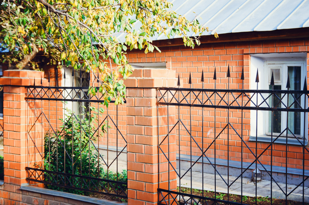 An image of a metal fence with bricks
