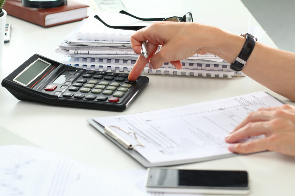 woman using calculator to compute for her budget with other documents in the table