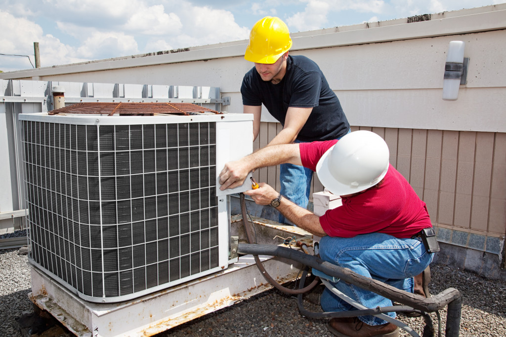 Workers fixing an HVAC unit on a building roof