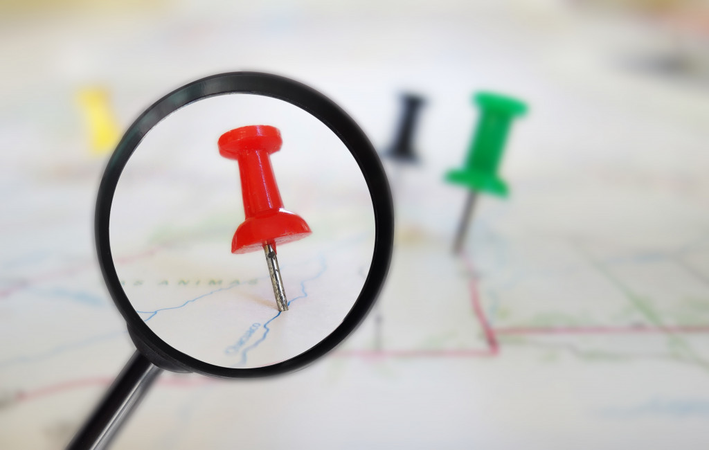 red push pin on a map under a magnifying glass
