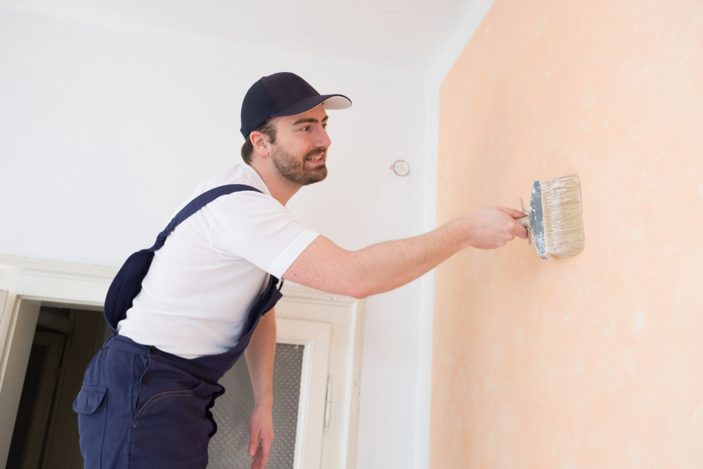 man painting wall a shade of pink or beige