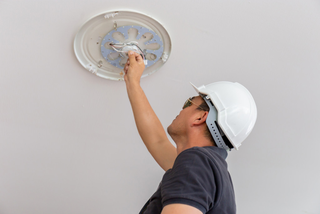 worker replacing light bulb on the ceiling