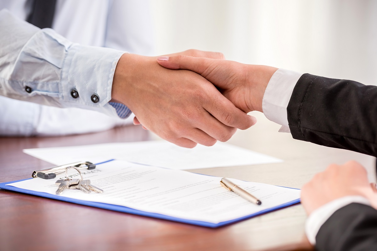 woman shaking hands with contract on the table