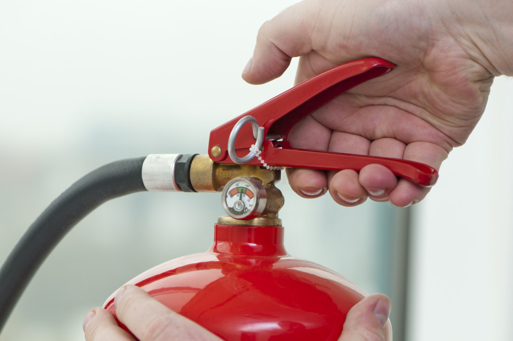 A hand squeezing the trigger of a fire extinguisher