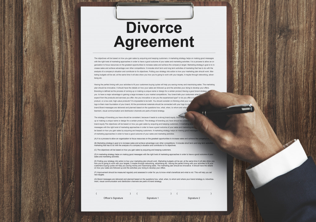 a hand signing a divorce agreement paper