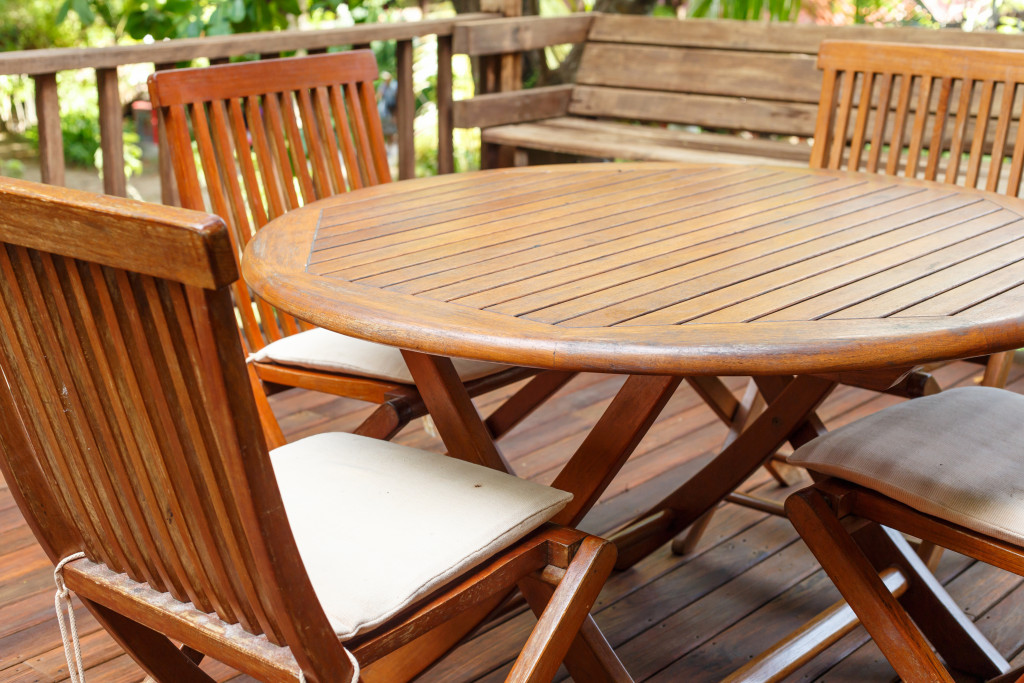 a teak wood furniture consists of table and chairs in a terrace