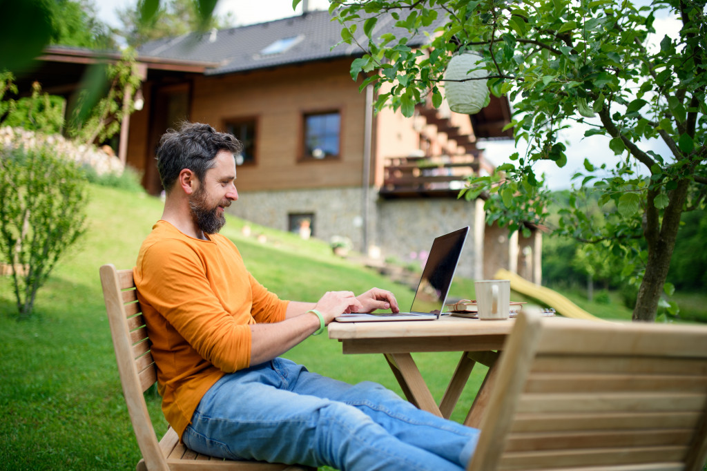 a man working with his laptop in his house's outdoors