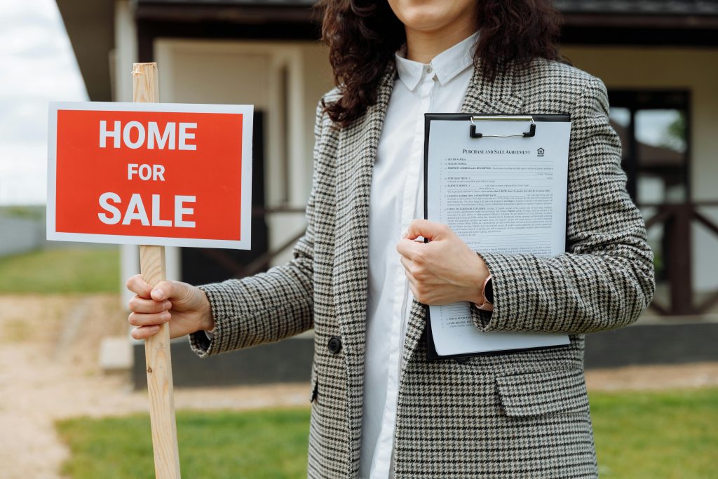 real estate agent holding 'home for sale' signage